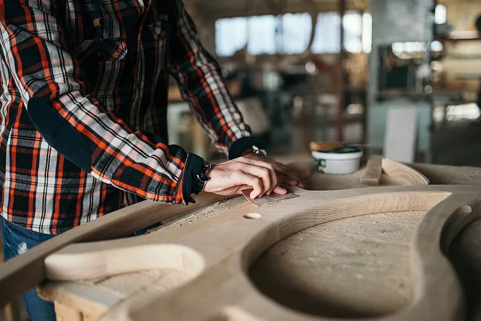 Context photograph: Craftsman shaping wood in a workshop during daylight hours with focus on precision and detail in woodworking; timber context, not an identified product or supplier on this page.